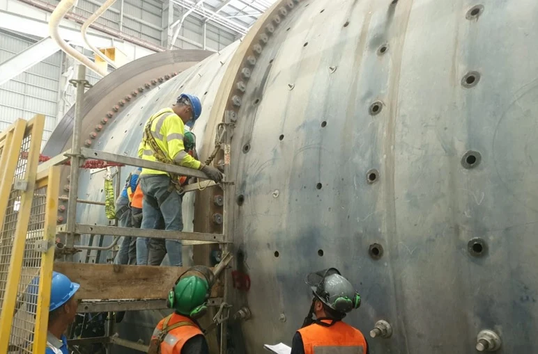 Técnico sobre andamio tensando pernos en el manto de un gran molino